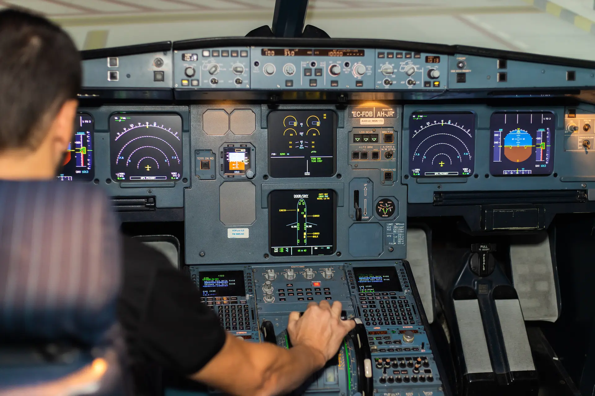 Piloto con la mano en las palancas de empuje del simulador Airbus A320